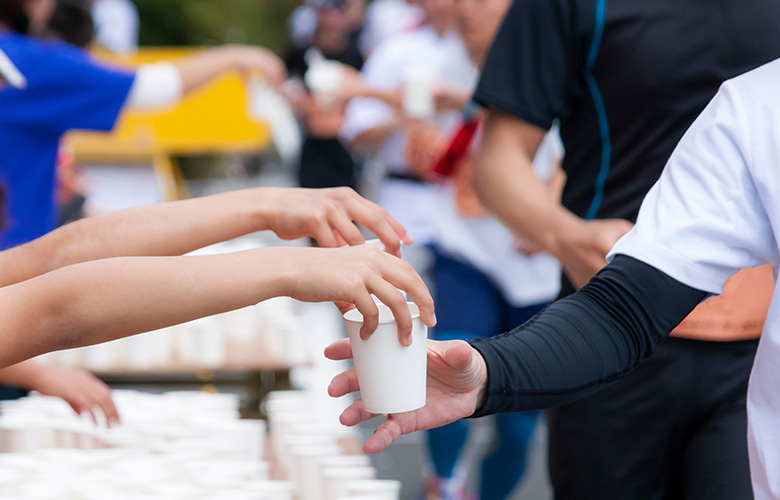 マラソン大会で給水所で水を渡す様子